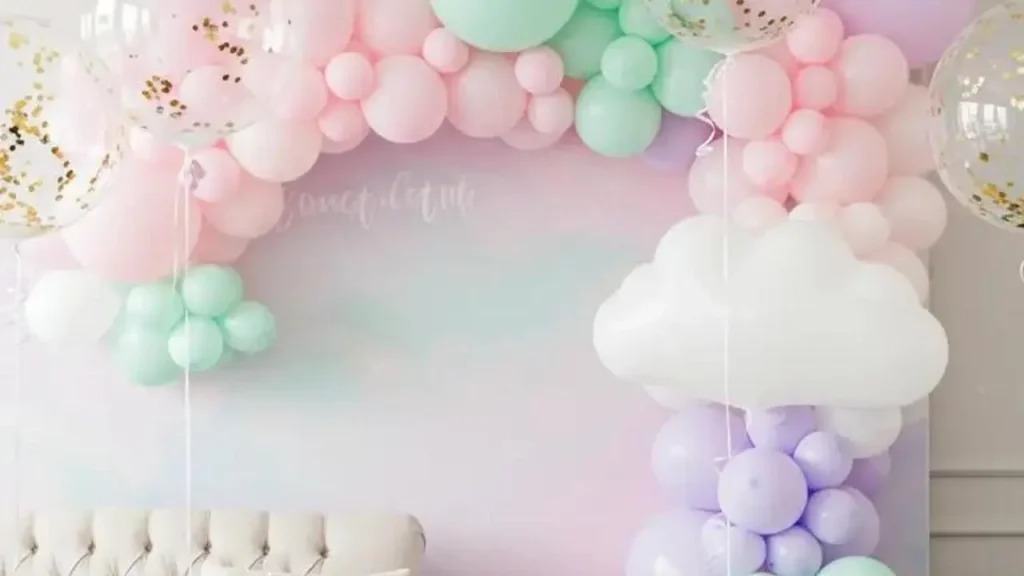 Feestelijke ballondecoraties met een pastelkleurige boog van ballonnen, confetti en een wolkje, voor een woonkamerfestival.