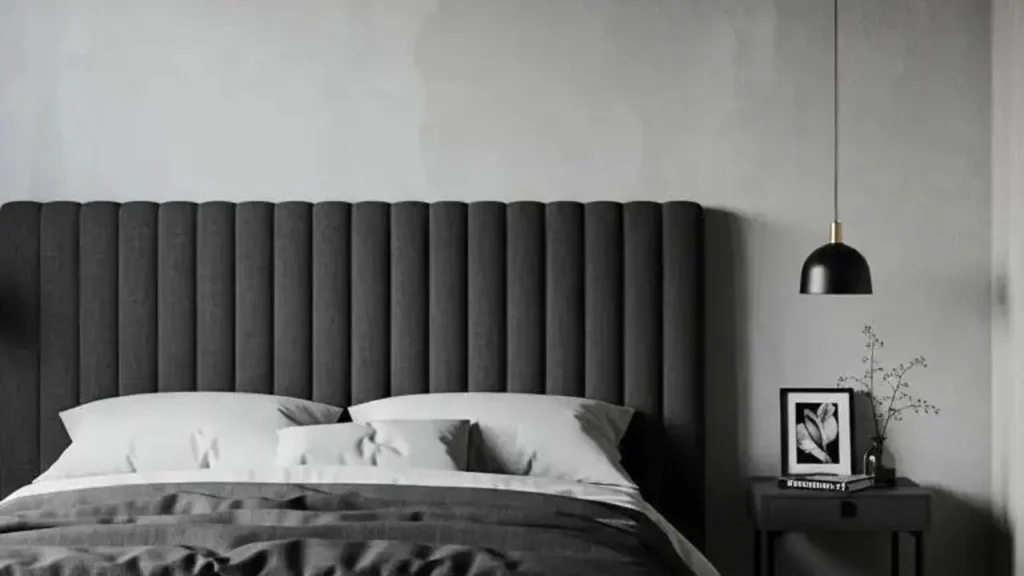 Slaapkamer met statement hoofdbord van stof, wit beddengoed en minimalistische lamp.