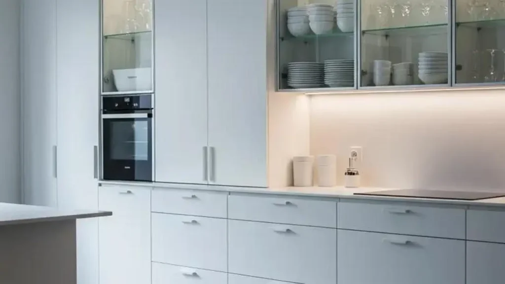 Servies mooi presenteren: een witte keuken met porselein en glazen in een kast.