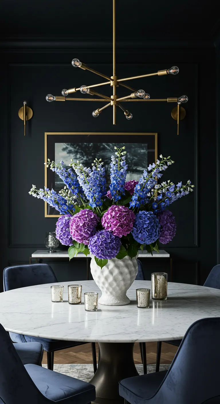Ronde eettafel met donkere muren, een groot boeket van paarse en blauwe bloemen en kaarsjes.
