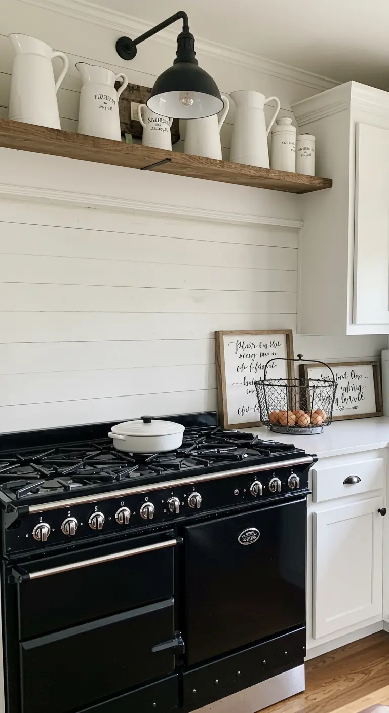 Zwart farmhouse fornuis met witte shiplap muur en houten plank met witte kannen.