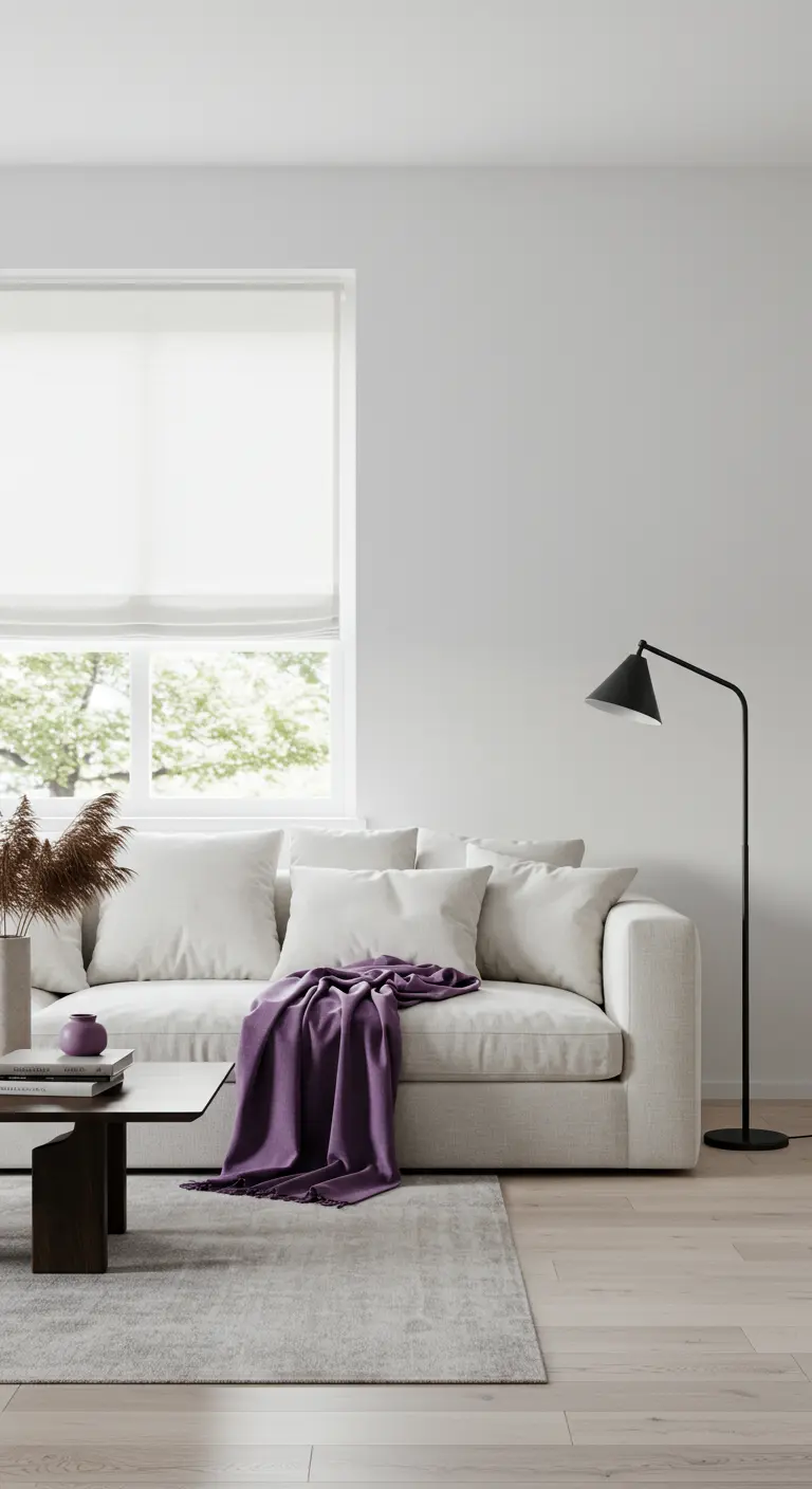 Minimalistische woonkamer met witte bank, paars plaid, zwarte lamp en houten tafel.