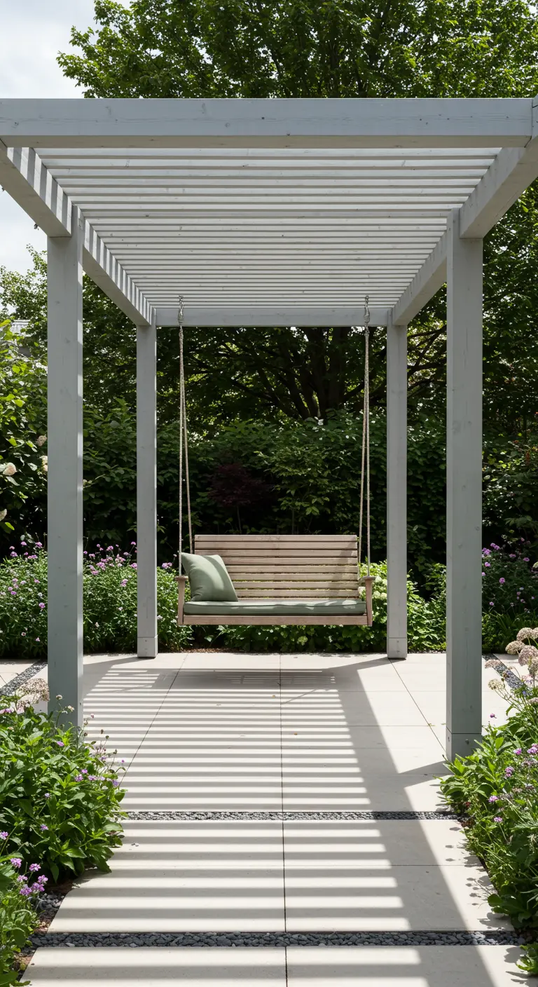 Houten schommel met groen kussen hangend onder een witte pergola.