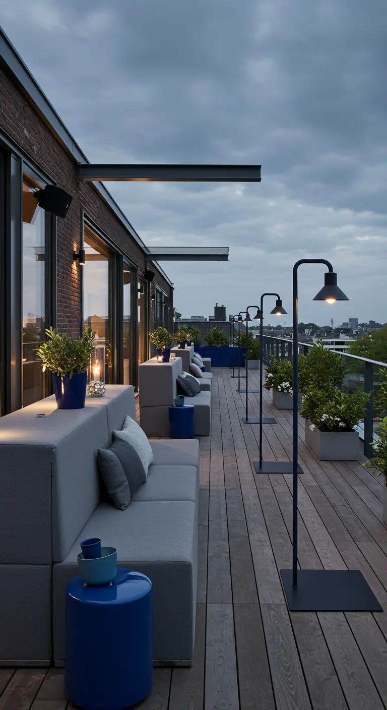 Modern dakterras met grijze loungebanken, blauwe accenten en strakke staande lampen.