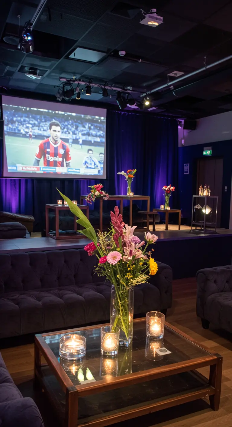 Lounge-opstelling met comfortabele banken, salontafel met kaarsen en bloemen, en een groot projectiescherm.