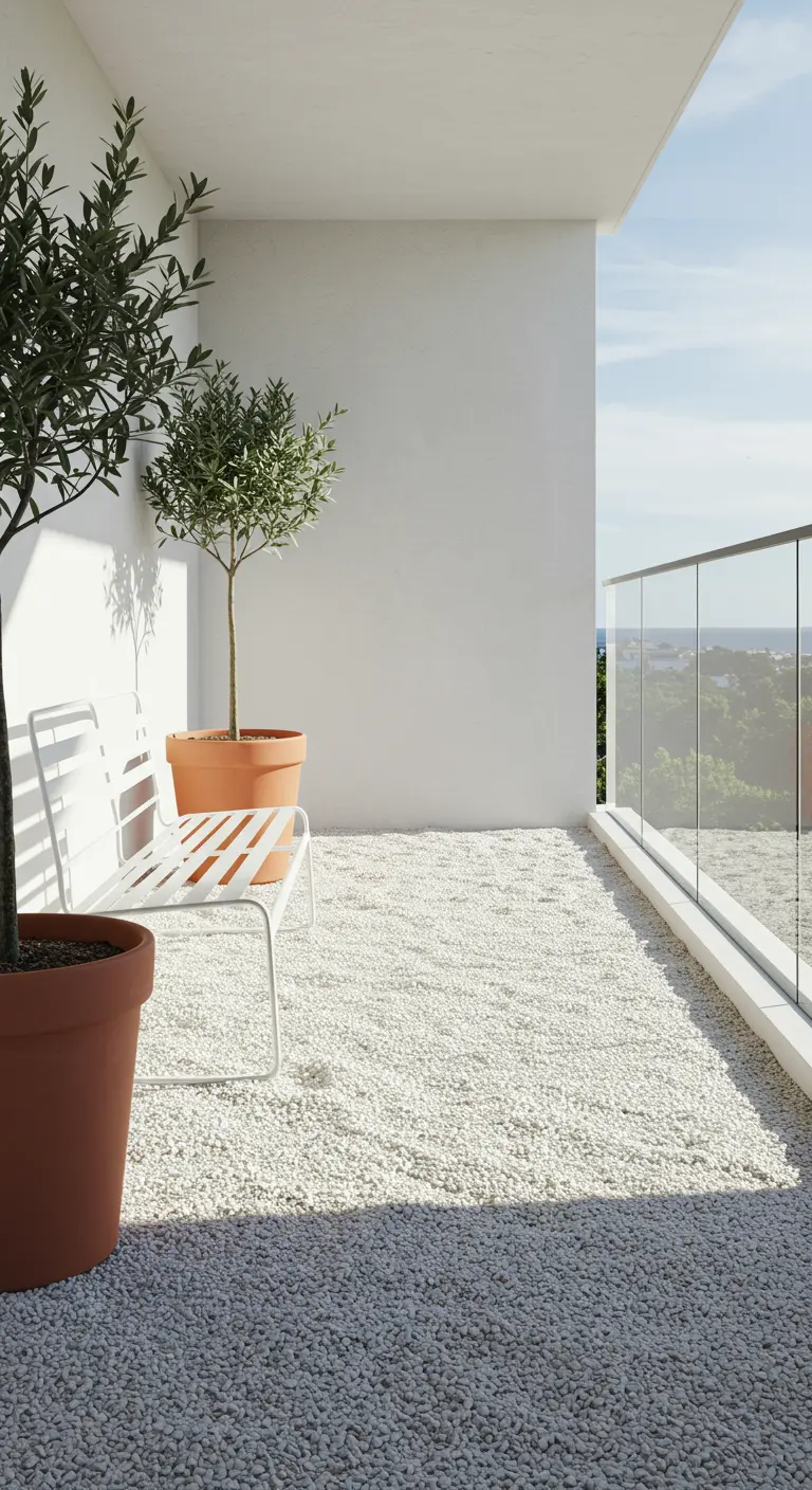 Wit balkon met witte kiezelvloer, olijfbomen in potten en een wit metalen bankje.