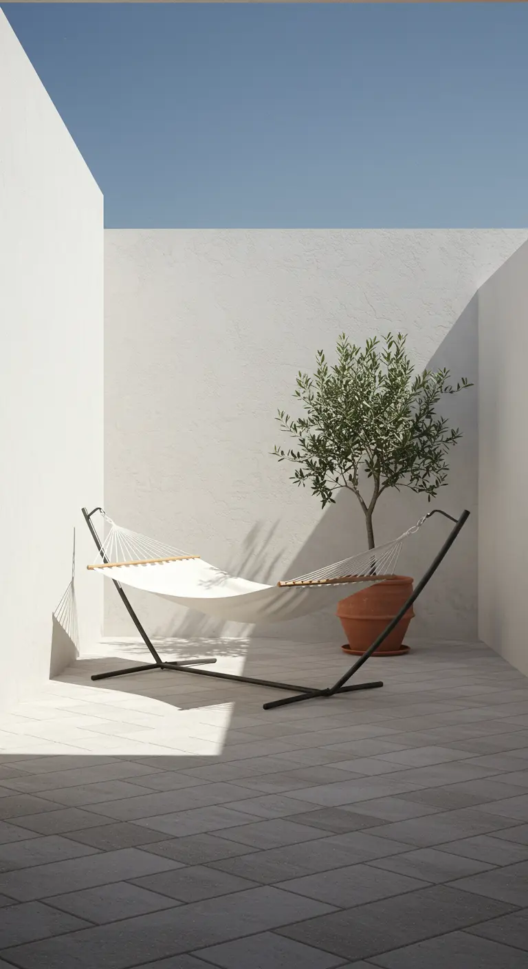 Witte hangmat op standaard in minimalistische patio met olijfboom.