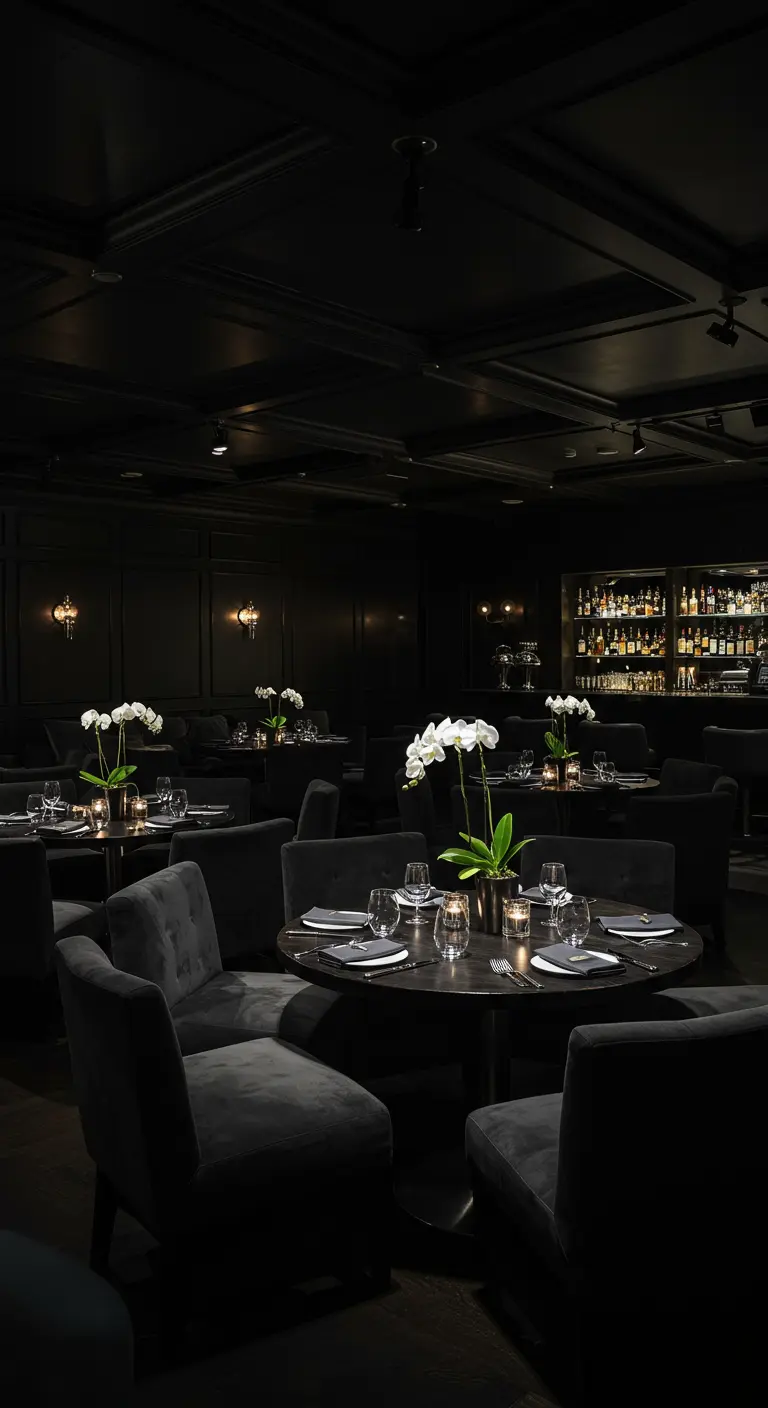 Chic restaurant met zwarte tafels, witte orchideeën en donkere stoelen.
